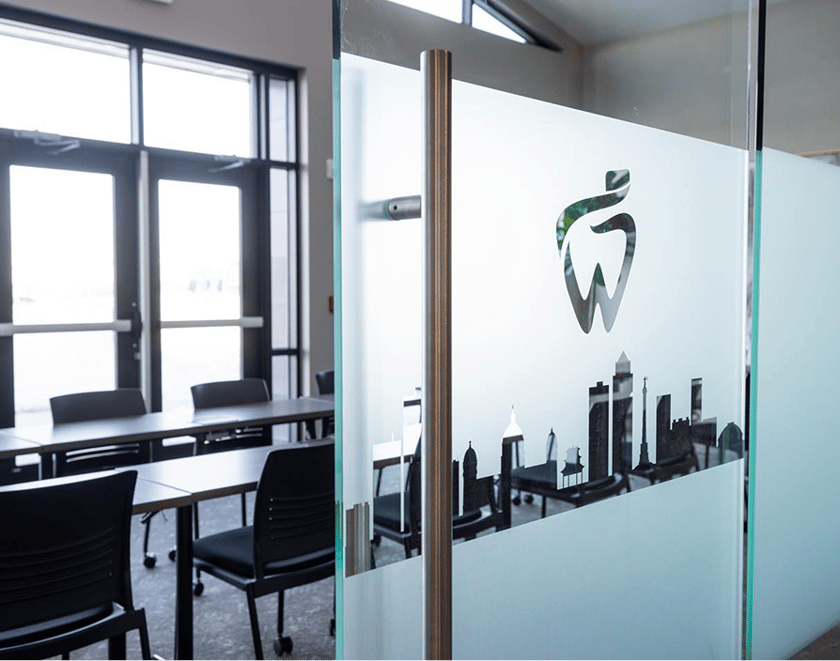 Modern dental office entrance with frosted glass door featuring a tooth logo